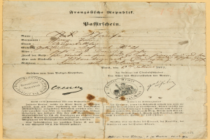 Ein altes, vergilbtes Dokument mit einem kreisförmigen, schwarz umrandeten Stempel, das schwarze Tintenbuchstaben enthält, wahrscheinlich ein Brief der deutschen Regierung.