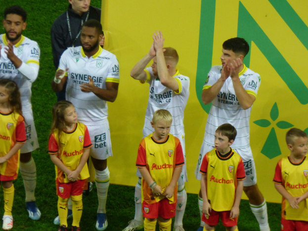Gruppe von Fußballspielern in Uniformen auf einem Ligue-1-Feld, die einen Sieg feiern