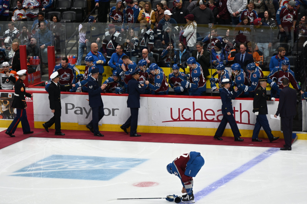 Ein Hockey-Spieler auf dem Eis umgeben von Teamkollegen und Gegnern, mit Zuschauern im Hintergrund bei einem Spiel zwischen Colorado Avalanche und San Jose Sharks am 24. März 2015.
