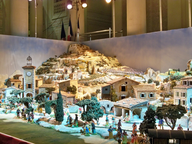 Ein detailliertes Miniatur-Modell einer Krippe in einem Museum ausgestellt, mit Figuren, Gebäuden und beleuchteten Elementen, die eine festliche Atmosphäre schaffen.