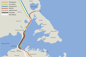 Karte einer Stadt mit einer roten Linie, die die geplante Bahnroute anzeigt, einschließlich Haltestellen und Details der umliegenden Gegend.