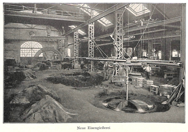 Schwarzes und wei\ues Foto eines Fabrikinneren mit Arbeitern, die Maschinen bedienen, Metallst"angen und -st"be, beschriftet mit "Neue Eisenglebeerei, die erste Fabrik in Deutschland" unten.