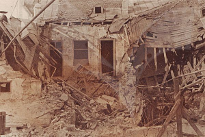 Ein altes Schwarz-Weiß-Foto eines baufälligen Gebäudes mit zerbrochenem Holz, bröckelnden Wänden und zerschlagenen Fenstern und Türen.