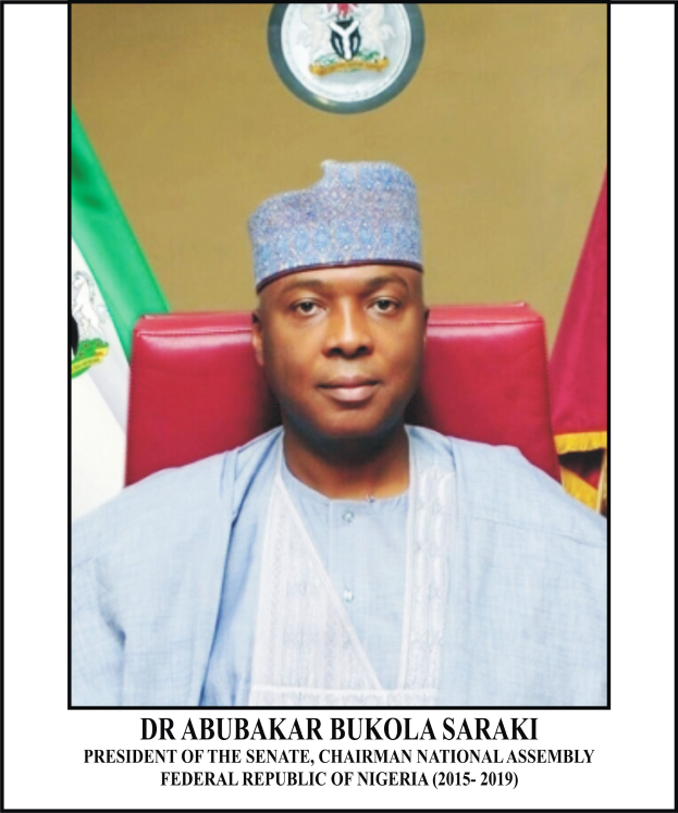 Dr. Abubakar Bukola Saraki, der Präsident des Senats, sitzt in einem Stuhl und trägt ein blaues Kleid und eine Mütze, mit zwei Flaggen und einem Logo an der Wand dahinter und einem Rahmen mit Namen unten.
