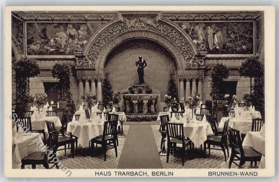 Schwarzes und weißes Foto eines alten Berliner Restaurant-Interieurs mit Tischen, Stühlen, Blumenvasen, Skulpturen, Pflanzen und einer Statue im Hintergrund.