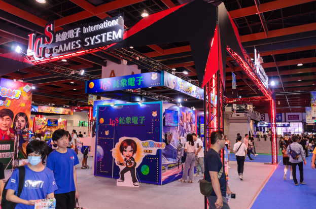 Eine Gruppe von Menschen geht durch einen Convention-Saal auf einer Gaming-Messe in China, einige tragen Taschen und halten Gegenstände, mit Ständen, Lichtern und einem Teppichboden im Hintergrund.