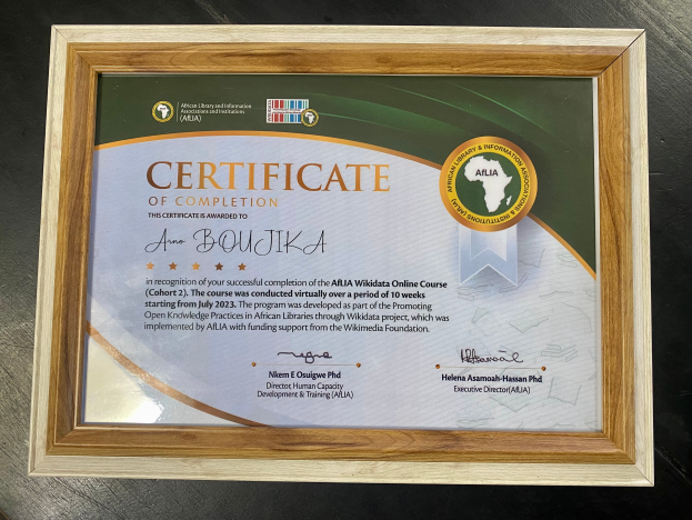 Ein gerahmtes Abschlusszertifikat liegt auf einem Tisch, mit Text, der den Abschluss anzeigt.