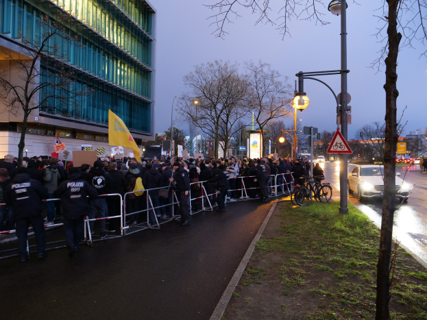 Große Gruppe von Menschen protestiert vor einem Gebäude in Berlin, hält Schilder mit Barrikaden und Fahrrädern im Vordergrund.