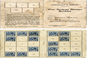 Ein altes Buch ist aufgeschlagen und zeigt eine Seite mit Text in einer klassischen Schriftart und Bildern von Menschen, die mit einer Vielzahl von Kriegsanleihestempeln in einem ordentlichen Muster bedeckt sind, die in hellen Rottönen und Blautönen bis hin zu gedämpften Grüntönen und Gelbtönen reichen.