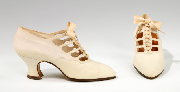 Weiße Schuhe mit Schnürsenkeln, spitzer Zeh, niedriger Absatz und Schleife auf weißem Hintergrund.