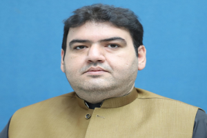 Ein Mann in brauner Weste und schwarzem Hemd steht vor einem blauen Hintergrund und sieht bedrückt und verzweifelt aus, wahrscheinlich wegen einer lebenslangen Haftstrafe.