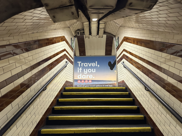 Eine Treppe in einer U-Bahn-Station mit einem Schild, das 'Reise, wenn du wagst' trägt.