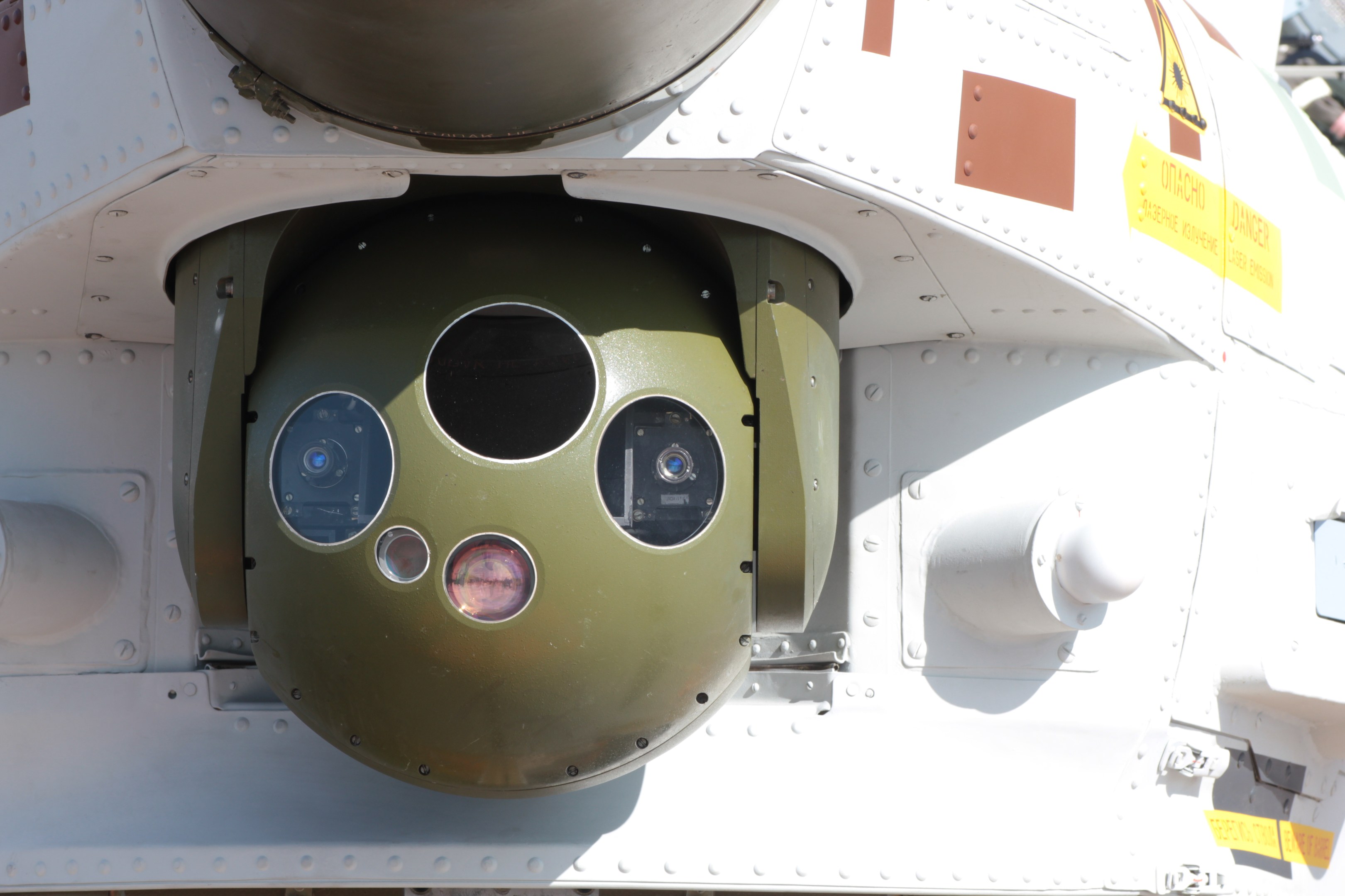 Nahaufnahme eines Militärfahrzeugs mit einer grün-weißen runden Rakete, die seitlich in einem Metallrahmen montiert ist.