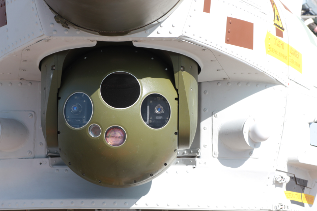 Nahaufnahme eines Militärfahrzeugs mit einer grün-weißen runden Rakete, die seitlich in einem Metallrahmen montiert ist.
