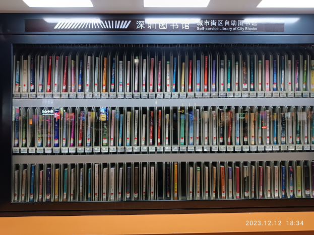 Eine gut beleuchtete Bibliothek mit hohen Bücherregalen voller Bücher, mit einem Textschild und einem Wasserzeichen unten, das an eine Selbstbedienungsbibliothek von Stadtblöcken erinnert.