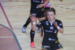 Eine Gruppe von Frauen in Sportuniformen beim Volleyballspielen auf einem Platz.
