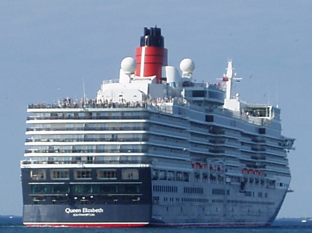 Große Kreuzfahrtschiff Queen Elizabeth auf dem Meer mit anderen Booten im Hintergrund bei klarem blauem Himmel.